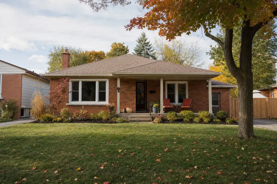 A red brick bungalow with a covered porch on a quiet street, autumn leaves on the lawn